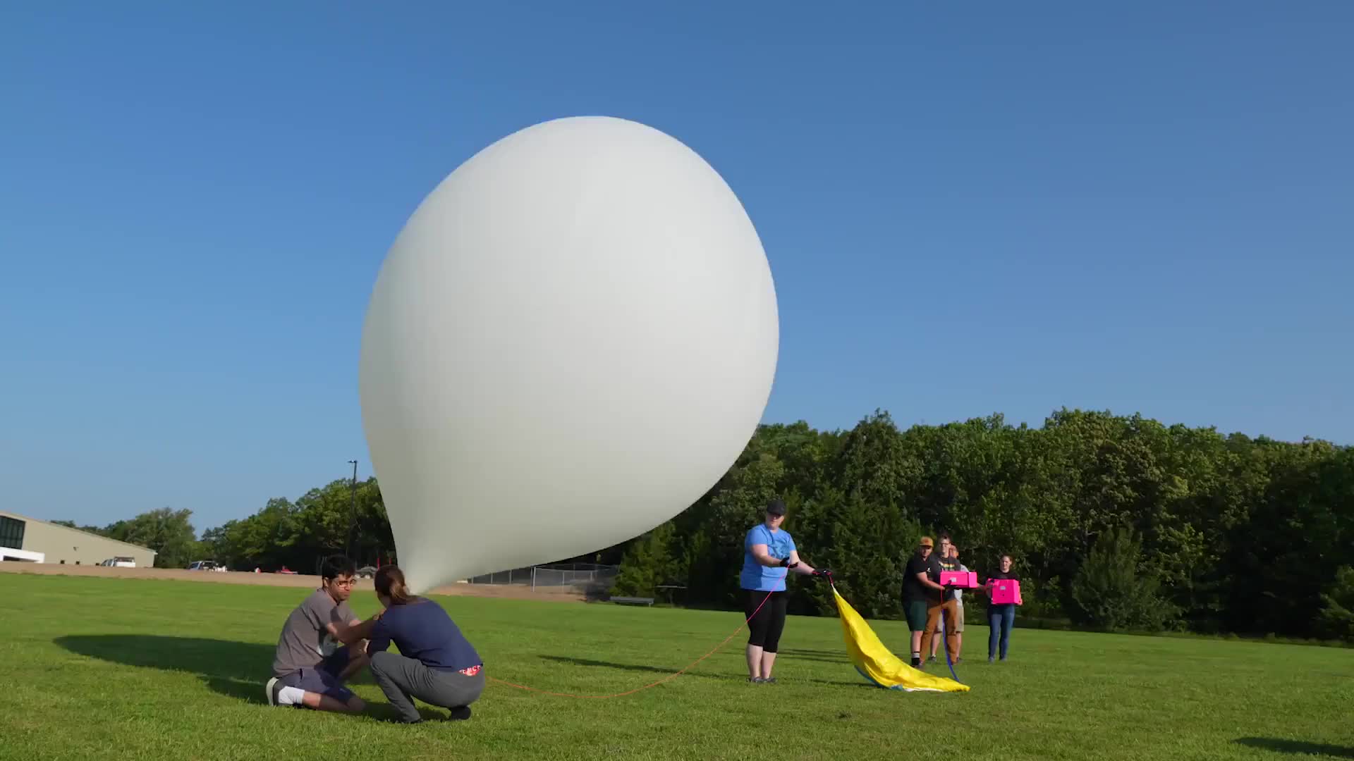 students launching a weather balloon against a blue sky